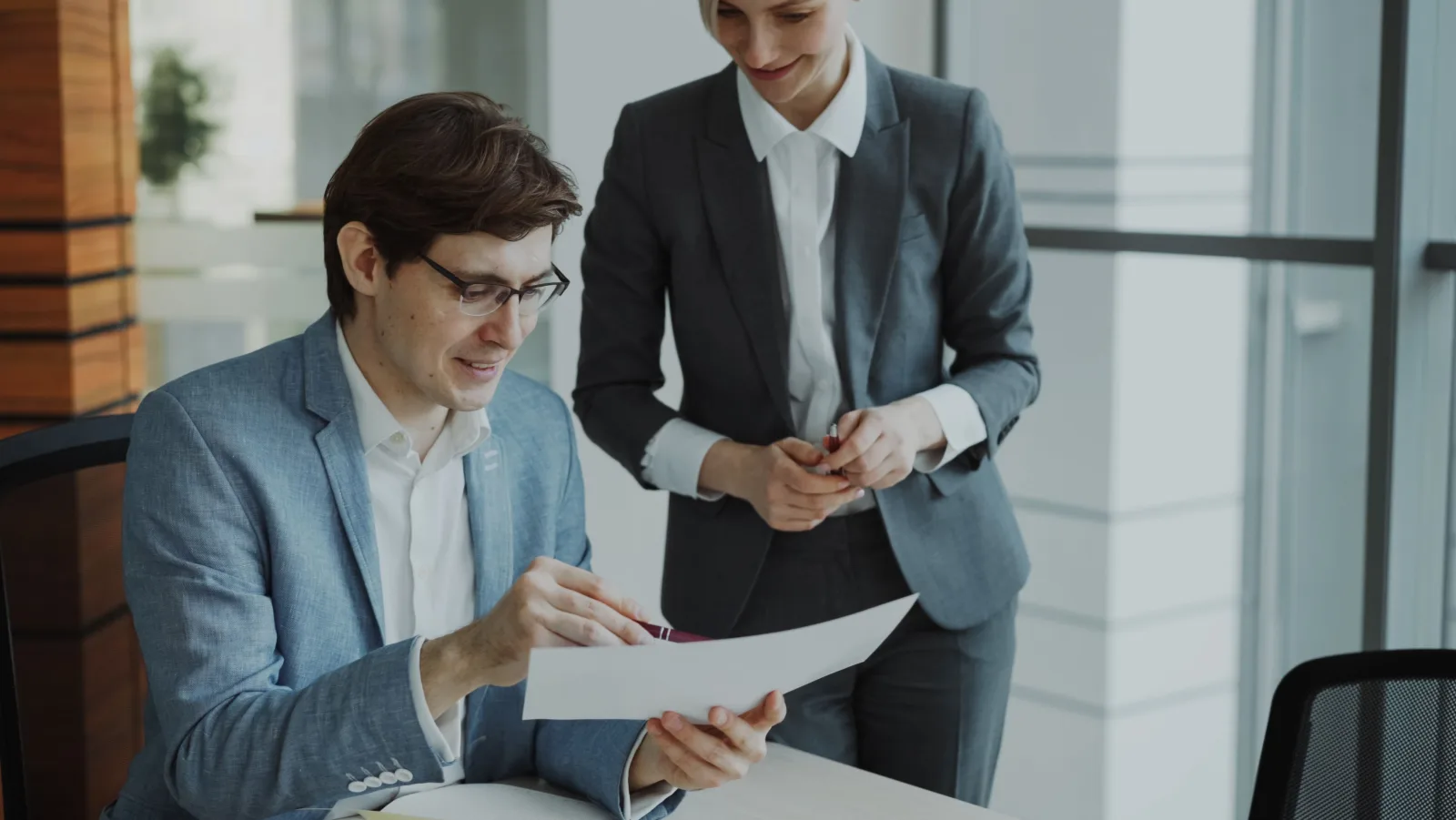 Two business professionals reviewing a document together in a bright office